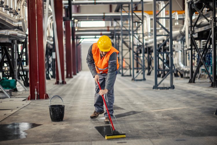 Industrial floor cleaning worker using squeegee in facility in Phoenix, AZ
