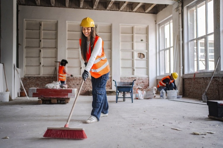 Interior cleanup crew sweeping large renovated room in Phoenix, AZ